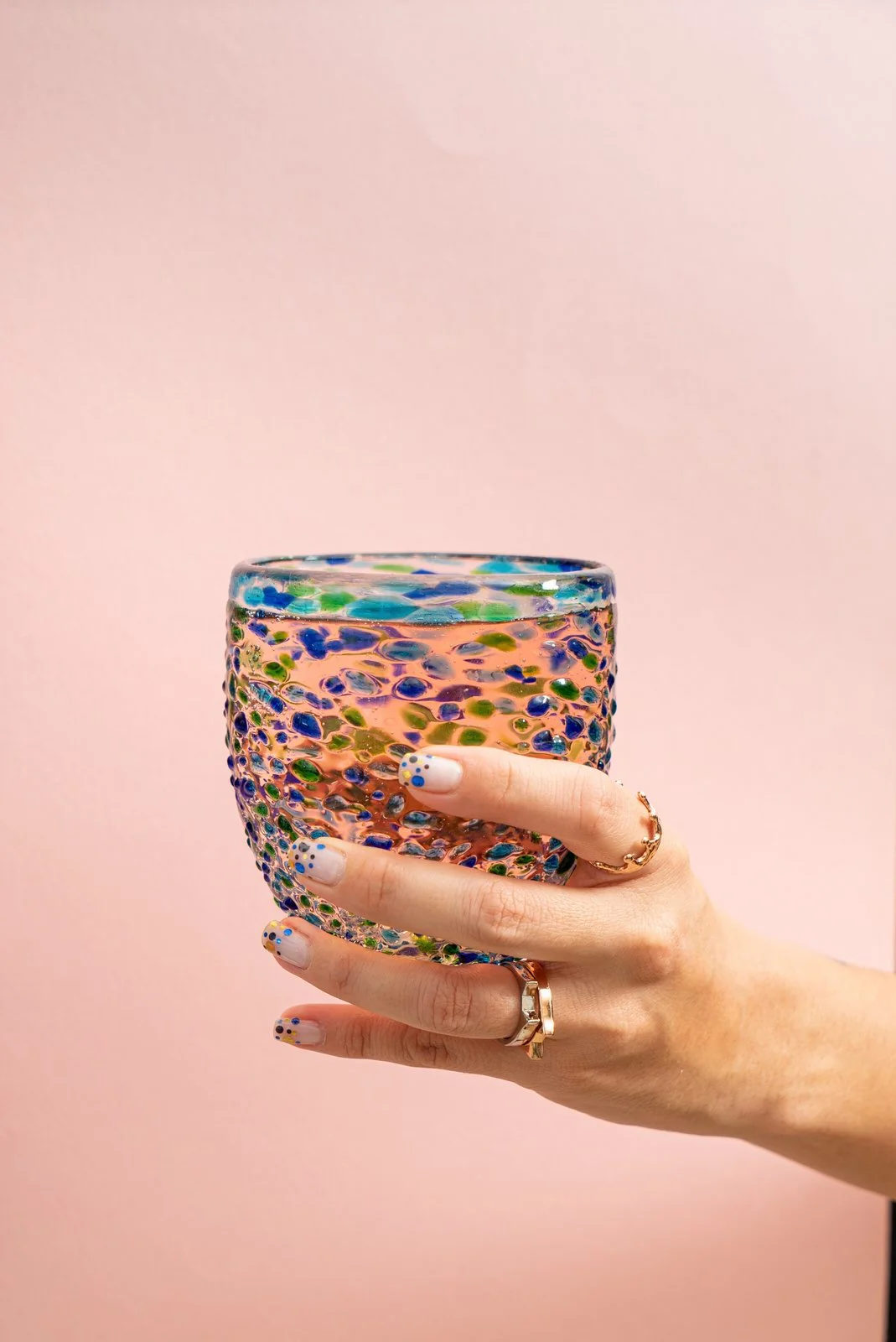 Hand holding a handmade Mexican blown-glass tumbler with multicolored speckles
