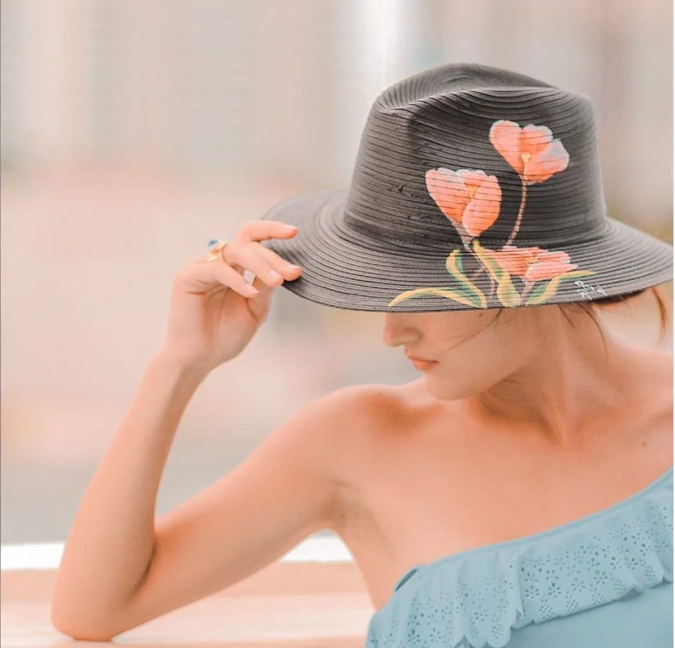 Woman wearing a dark handmade hat painted with pink flowers
