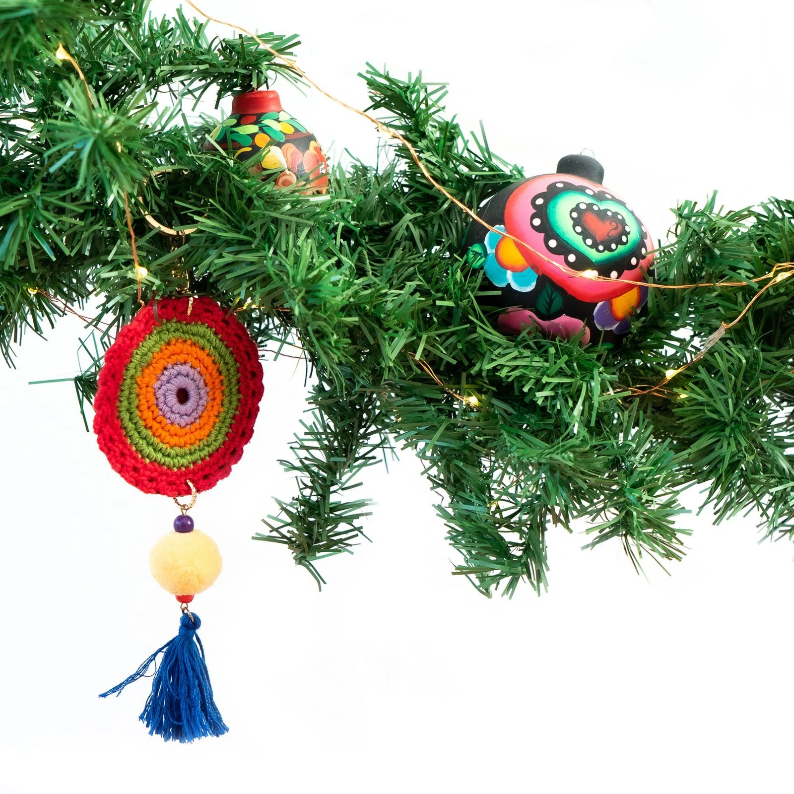 Colorful Mexican beaded ornaments hanging from green branches