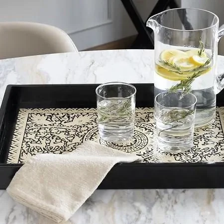 Decorative wooden serving tray with an intricate patterned base and drinking glasses